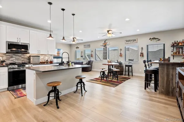 a kitchen with stainless steel appliances kitchen island granite countertop a refrigerator a stove a sink a dining table and chairs with wooden floor