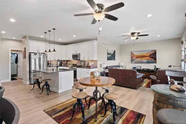 a living room with stainless steel appliances lots of furniture and kitchen view