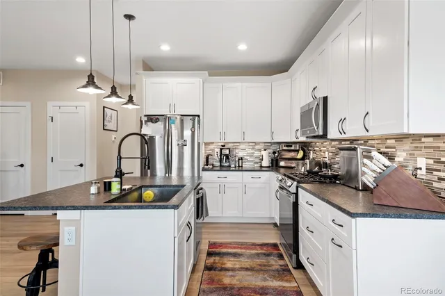 a kitchen with stainless steel appliances granite countertop a sink stove and refrigerator