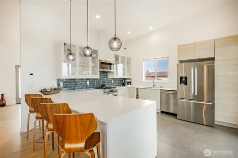 a kitchen with stainless steel appliances kitchen island granite countertop a stove top oven a sink dishwasher and a refrigerator with wooden floor