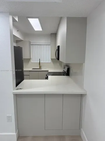 a kitchen with a sink a refrigerator and cabinets