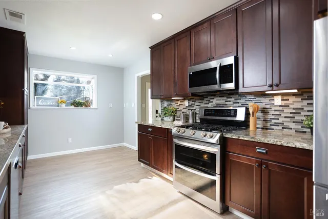 a large kitchen with stainless steel appliances a large counter top a stove a sink and a refrigerator