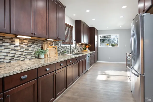 a kitchen with stainless steel appliances granite countertop a refrigerator and a stove top oven