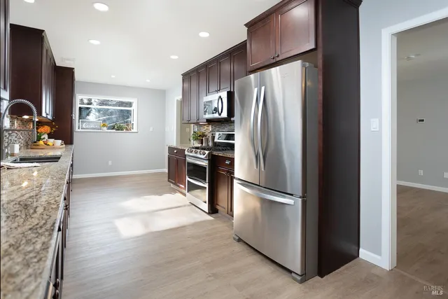 a kitchen with stainless steel appliances granite countertop a stove refrigerator and microwave