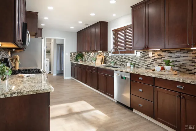 a kitchen with stainless steel appliances granite countertop wooden cabinets a stove top oven a sink and dishwasher