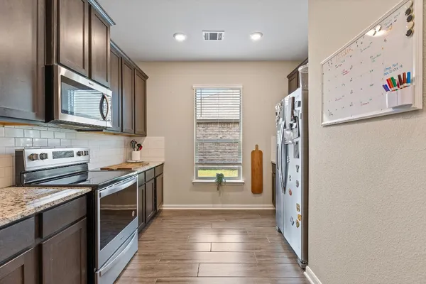 a kitchen with stainless steel appliances granite countertop a refrigerator a stove top oven a sink and dishwasher