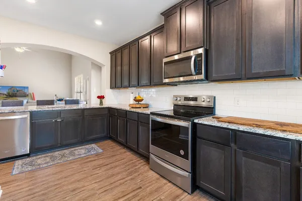 a kitchen with stainless steel appliances granite countertop wooden cabinets a stove top oven and granite counter tops