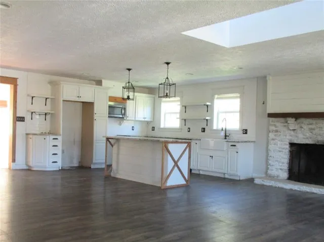 a kitchen with stainless steel appliances granite countertop a refrigerator a stove oven and white cabinets with wooden floor