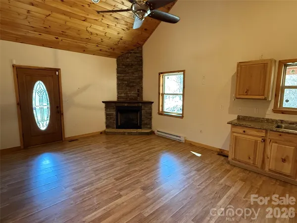 a big room with wooden floor a fireplace and windows