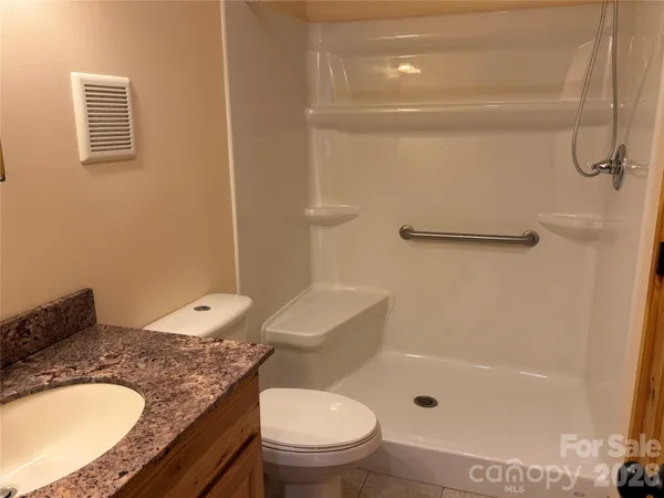 a bathroom with a granite countertop sink toilet and shower