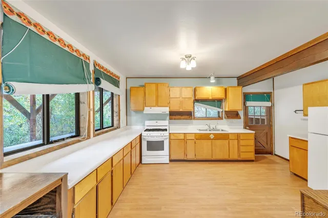 a large kitchen with kitchen island a large window a sink and stainless steel appliances