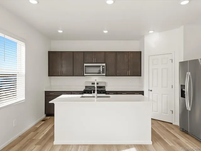 a kitchen with stainless steel appliances granite countertop a refrigerator a sink a stove a microwave and island