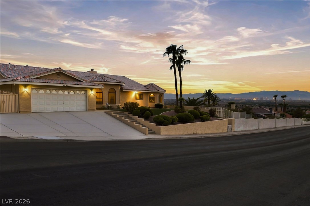 1068 Calico Ridge Drive Henderson, NV 89011 - Photo 38 of 38 Dramatic sunset skies frame this elegant single-level residence showcasing a wide concrete driveway and tile roof.