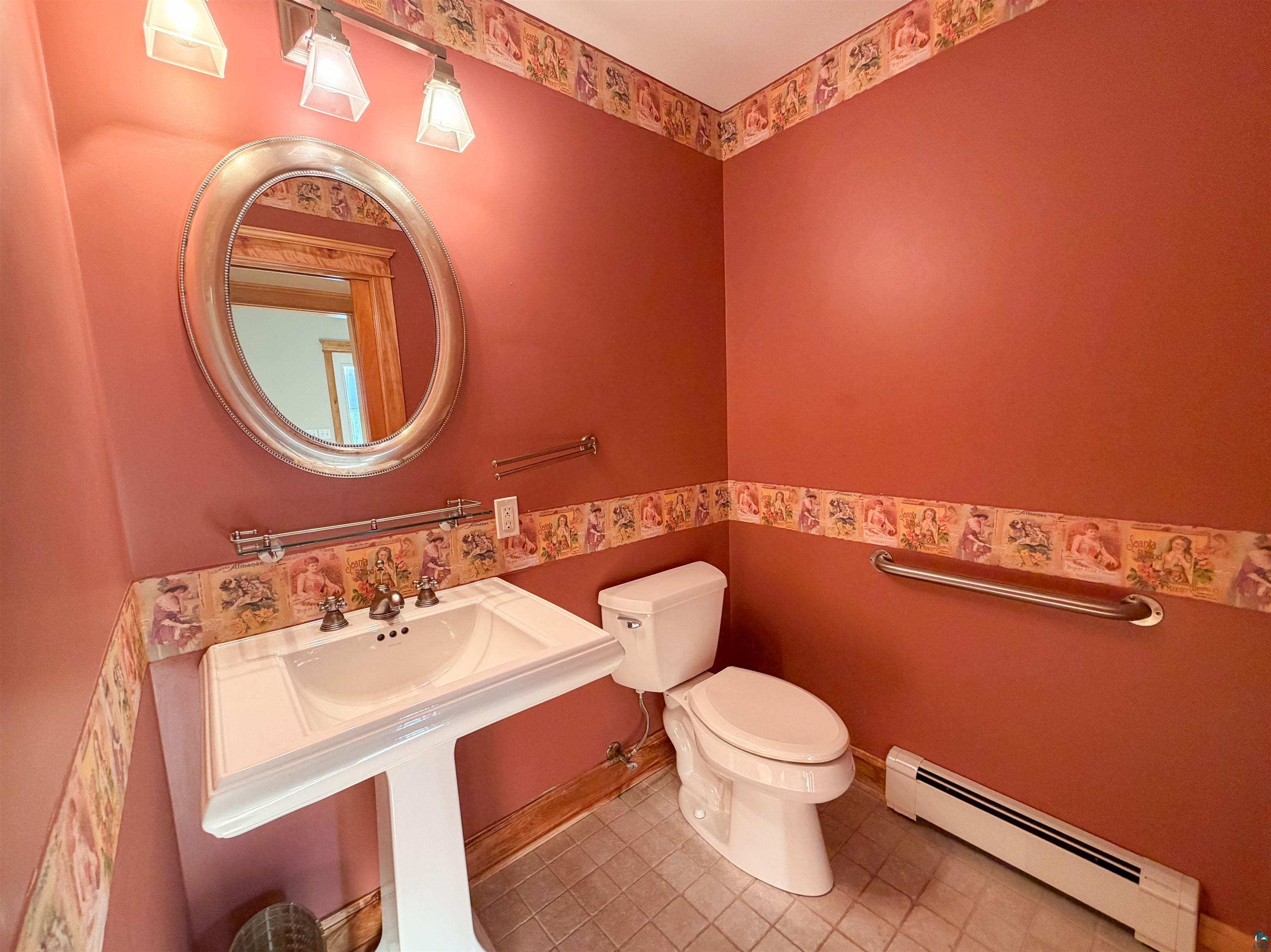 13 West 8th Street Duluth, MN 55806 - Photo 16 of 57 Pedestal sink with chrome-finish faucet, an oval mirror, and a wall-mounted light fixture