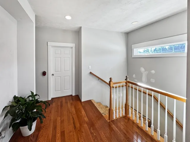 a view of a hallway with wooden floor and stairs