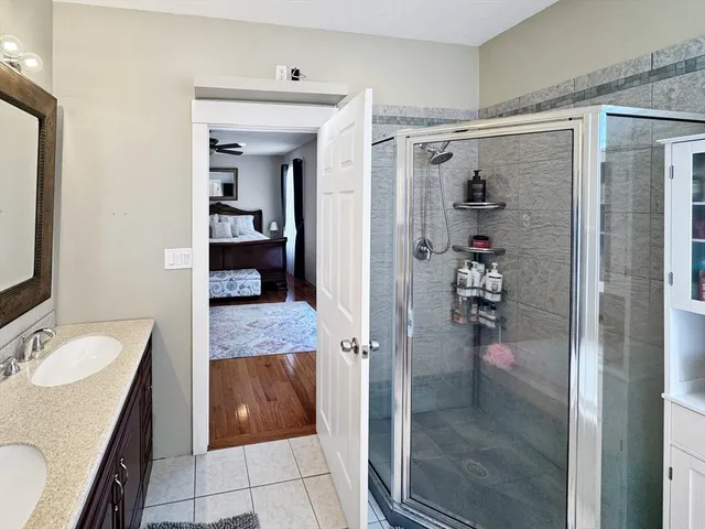 a bathroom with a granite countertop sink a mirror and shower