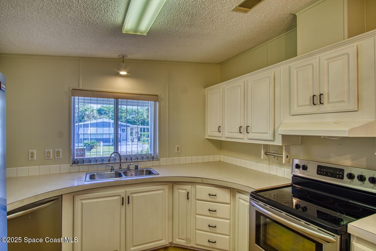 2390 Coconut Palm Drive Palm Bay, FL 32905 - Photo 9 of 27 a kitchen with stainless steel appliances granite countertop a sink a stove and cabinets