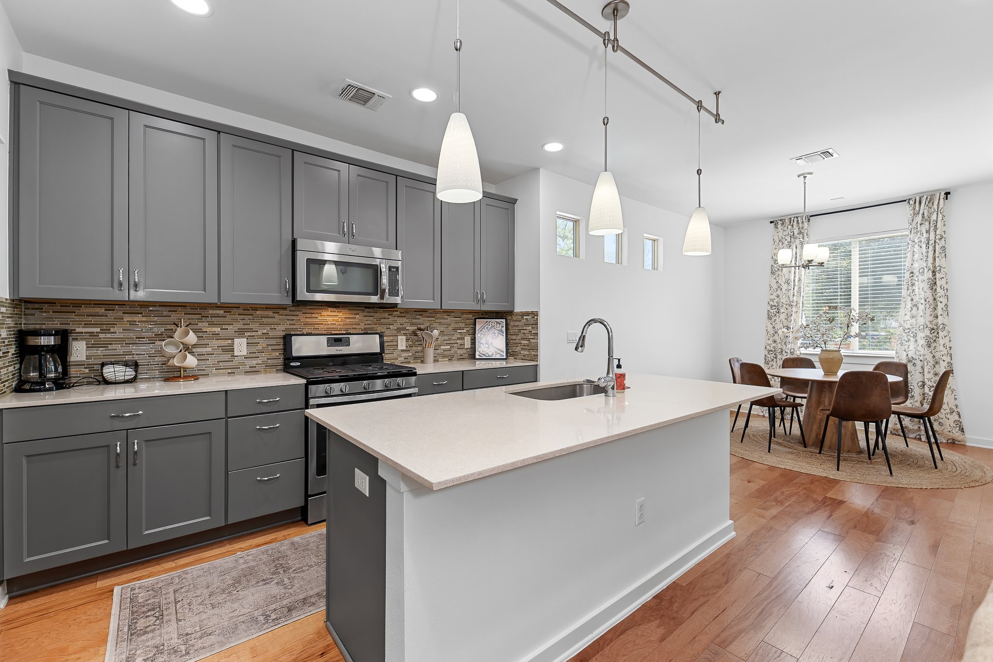 4408 Banister Lane, Unit B Austin, TX 78745 - Photo 11 of 28 a open kitchen with stainless steel appliances granite countertop a stove top oven a sink dishwasher a dining table and chairs with wooden floor