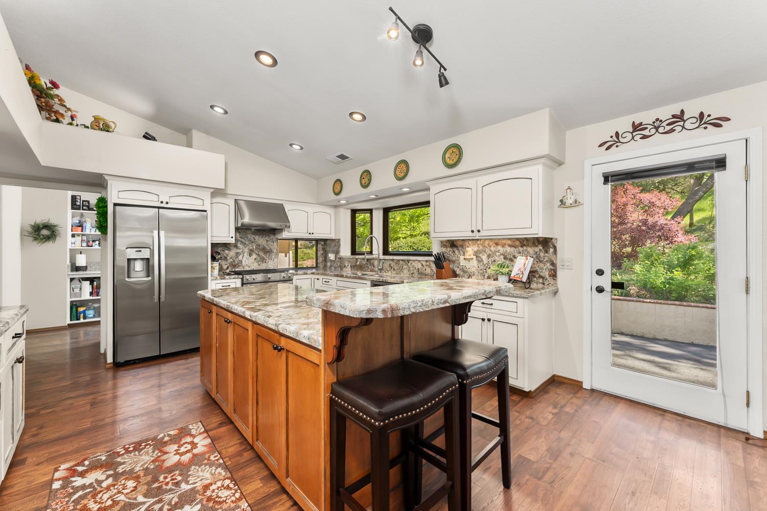19461 Fiddletown Road Fiddletown, CA 95629 - Photo 11 of 62 a kitchen with stainless steel appliances granite countertop a refrigerator a sink dishwasher a stove and white cabinets with wooden floor