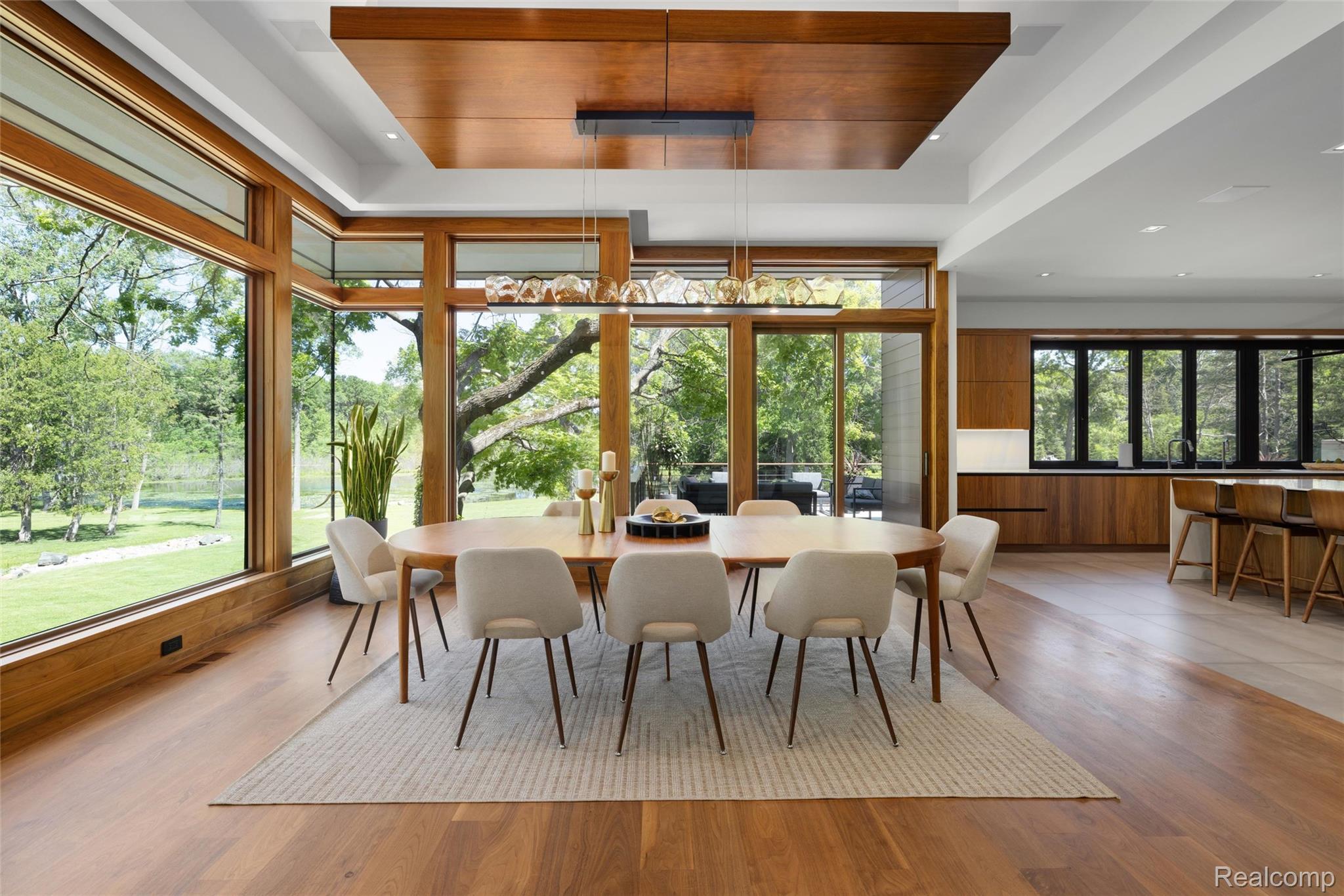2700 Squirrel Road Bloomfield Hills, MI 48304 - Photo 12 of 83 Dining area featuring floor-to-ceiling windows with wood framing, wood-finish flooring, a wood-paneled ceiling accent, and a contemporary linear chandelier