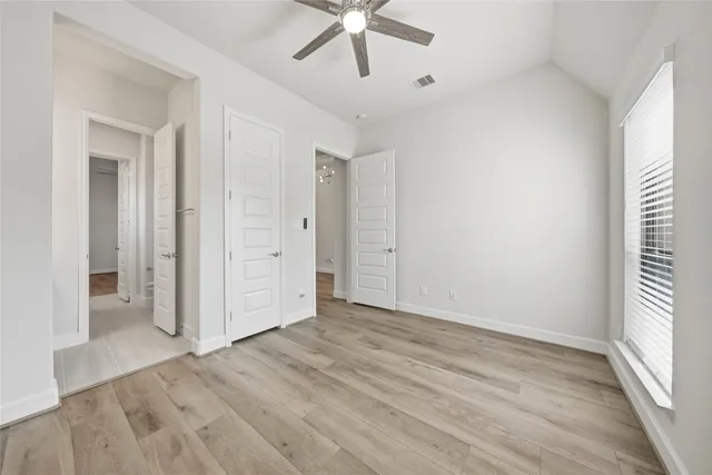 an empty room with wooden floor and ceiling fan