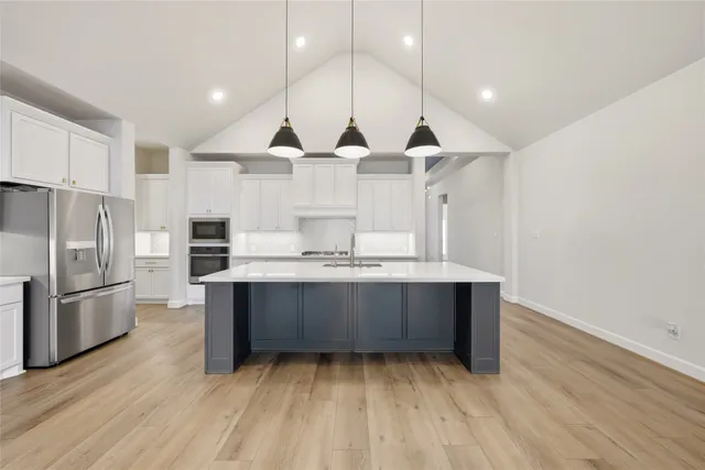 a view of kitchen with stainless steel appliances wooden floor and large window