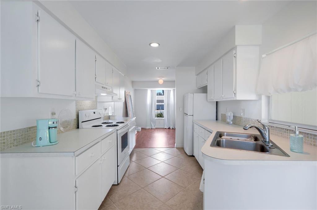 59 Hilo Court, Unit 59 Naples, FL 34112 - Photo 11 of 25 a kitchen that has a lot of cabinets a sink and appliances in it