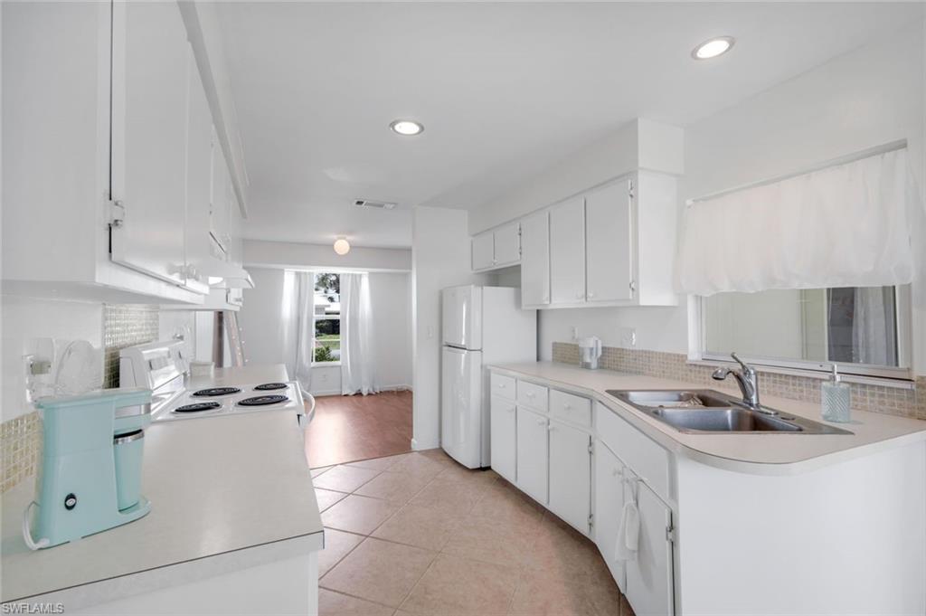 59 Hilo Court, Unit 59 Naples, FL 34112 - Photo 12 of 25 a kitchen with stainless steel appliances kitchen island a sink a stove a refrigerator and cabinets