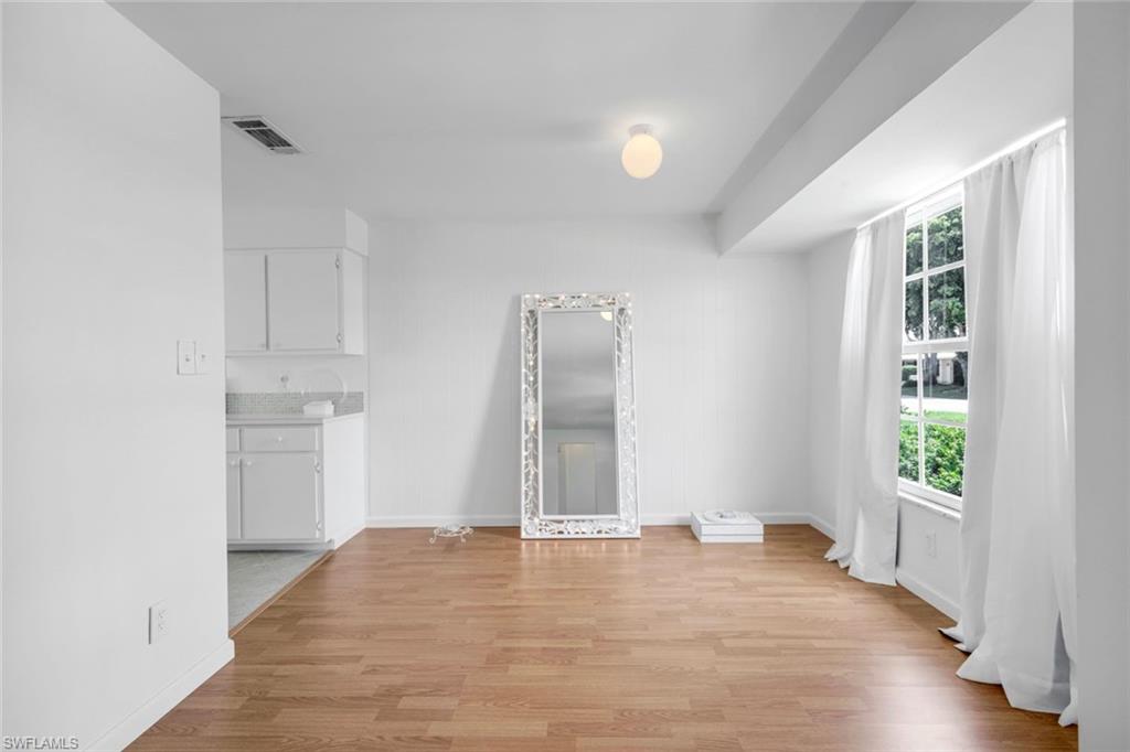 59 Hilo Court, Unit 59 Naples, FL 34112 - Photo 8 of 25 an empty room with wooden floor and windows