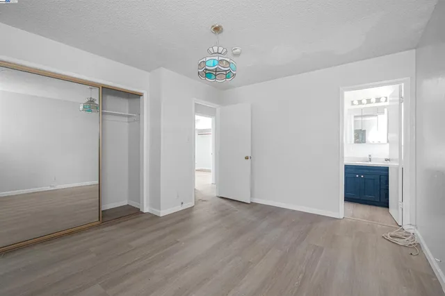 a view of an empty room with wooden floor and closet