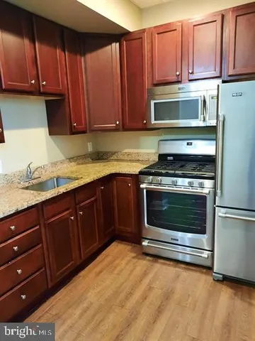 a kitchen with granite countertop wooden cabinets stainless steel appliances and a sink