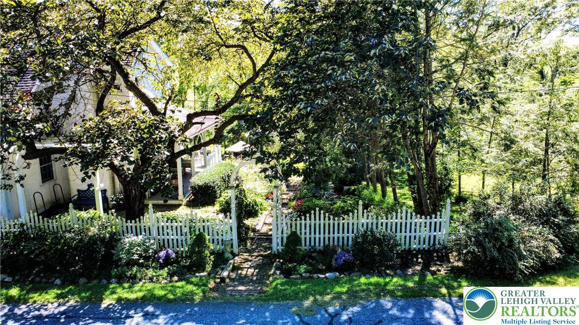 1731 Howell Road Easton, PA 18040 - Photo 7 of 60 Mature trees frame a charming fenced garden pathway leading toward the main structure.