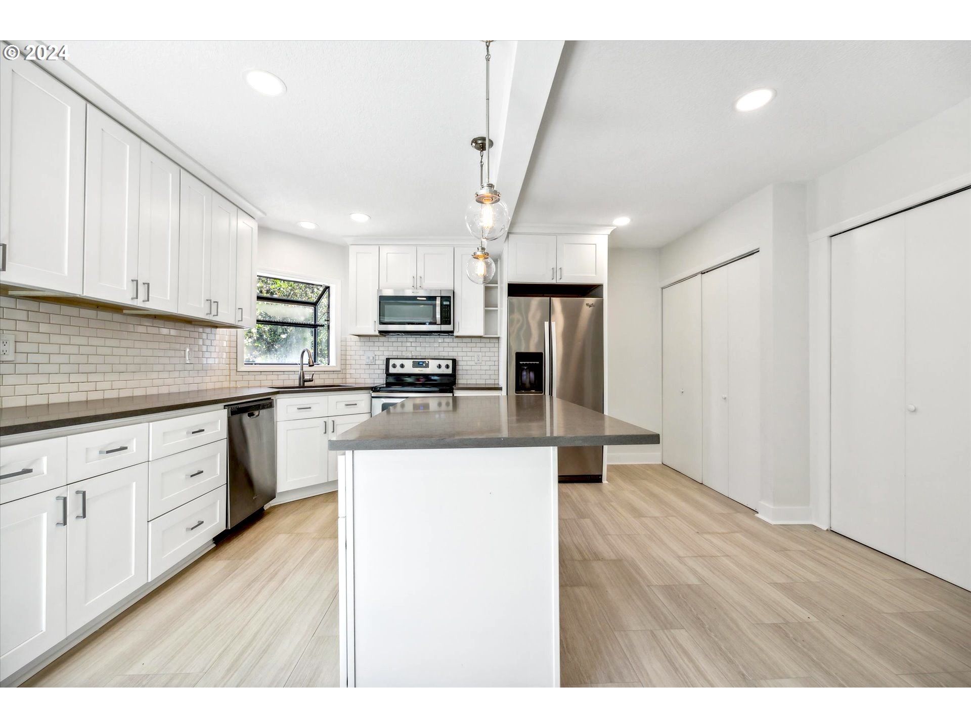 10097 Southwest Walker Road Portland, OR 97225 - Photo 5 of 44 a kitchen with stainless steel appliances kitchen island granite countertop a refrigerator a sink dishwasher and white cabinets with wooden floor