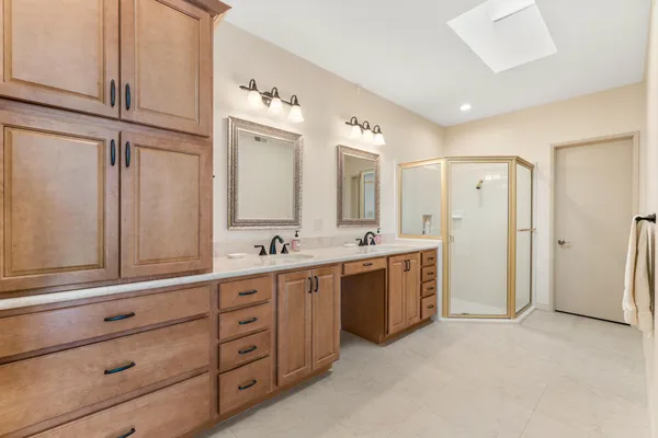 a spacious bathroom with a double vanity sink a mirror and a shower