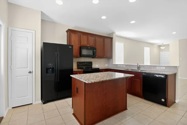a kitchen with stainless steel appliances granite countertop a stove a refrigerator and a sink
