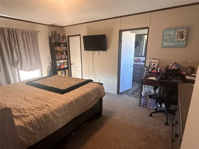 a bedroom with a bed a desk and a flat screen tv