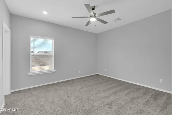 an empty room with a window and a fan