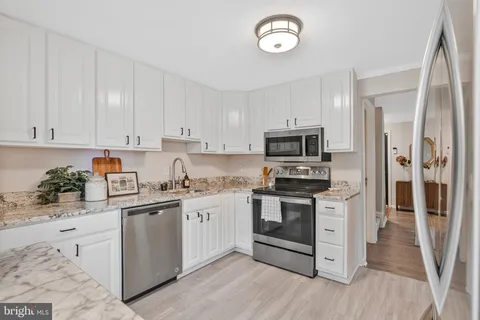 a kitchen with stainless steel appliances granite countertop a stove top oven a sink and dishwasher a refrigerator with wooden floor