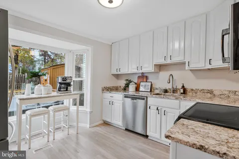 a kitchen with granite countertop white cabinets and white appliances