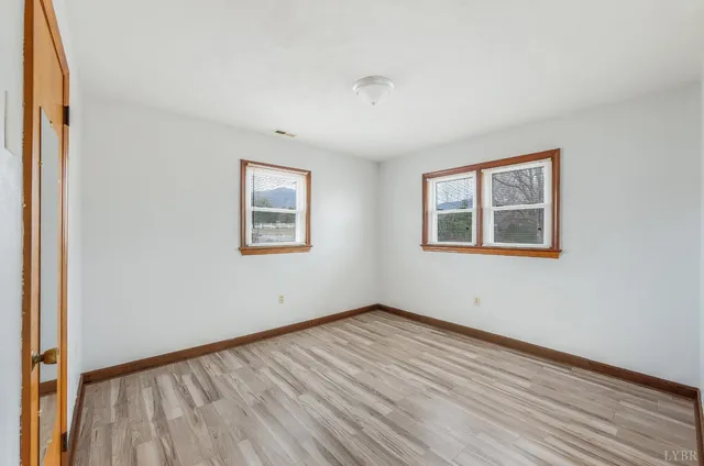 a view of an empty room with wooden floor and closet