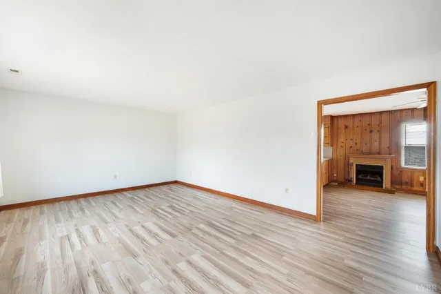 an empty room with wooden floor fireplace and windows