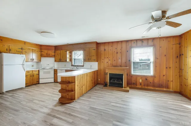 a large white kitchen with wooden floors and a fireplace