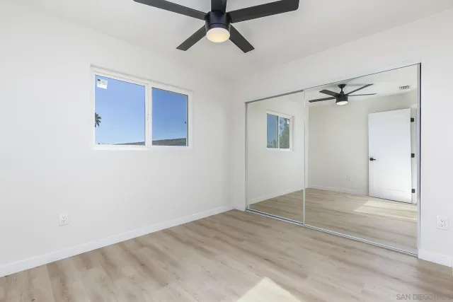 an empty room with wooden floor a ceiling fan and windows