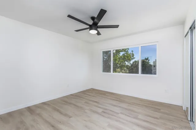 a view of empty room with wooden floor and windows