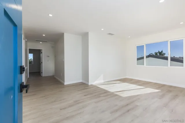 a view of an empty room with window and wooden floor