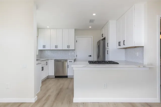 a kitchen with stainless steel appliances granite countertop a stove a sink and white cabinets