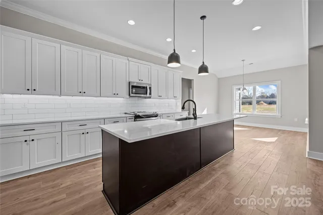a large kitchen with kitchen island a sink a center island and wooden floor