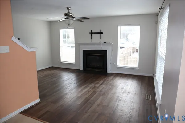 an empty room with wooden floor fireplace and windows