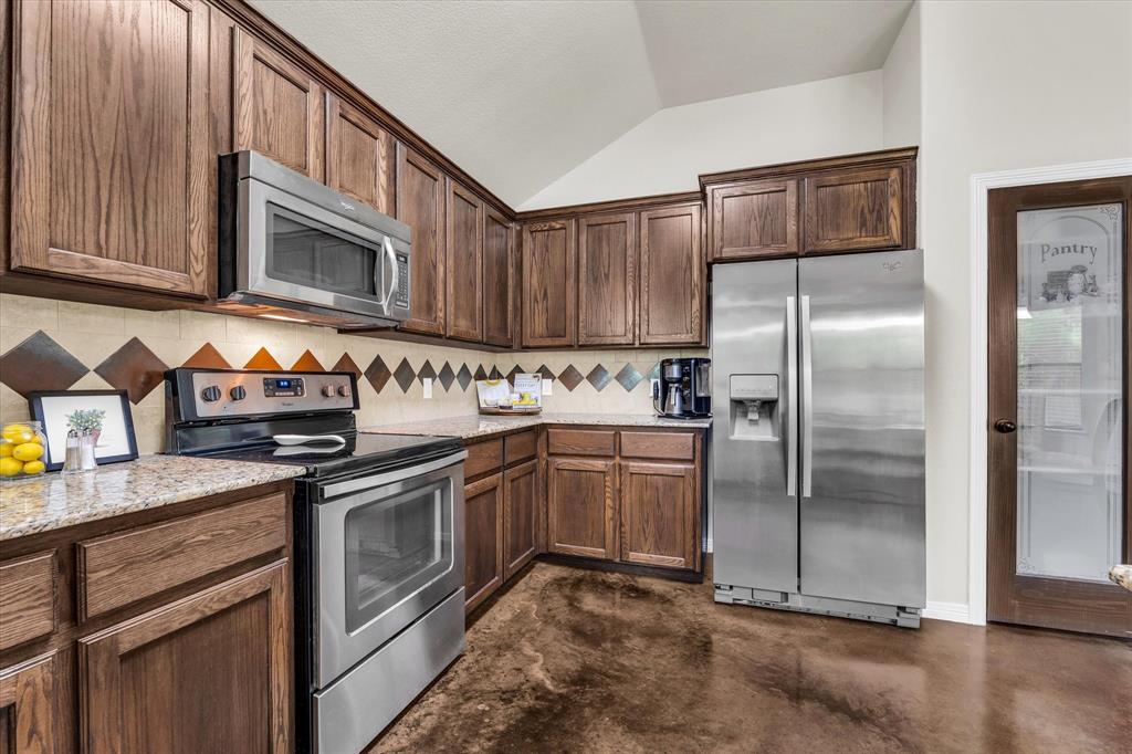 814 Springdale Circle Lorena, TX 76655 - Photo 8 of 37 Kitchen featuring wood cabinetry, stainless steel appliances, speckled countertops, and a patterned tile backsplash