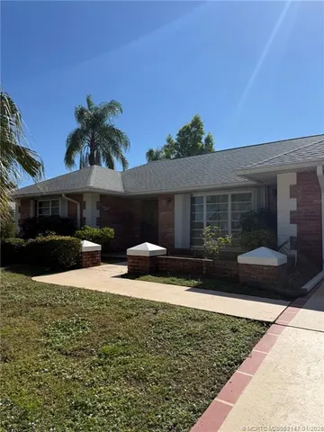 a front view of house with yard and trees in the background